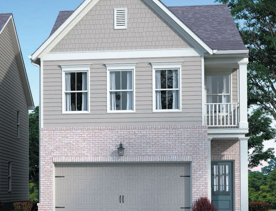 Two-story suburban house with light gray siding, brick accents, a double garage, two upstairs windows, a small balcony, and landscaping with bushes and orange flowers along the driveway.