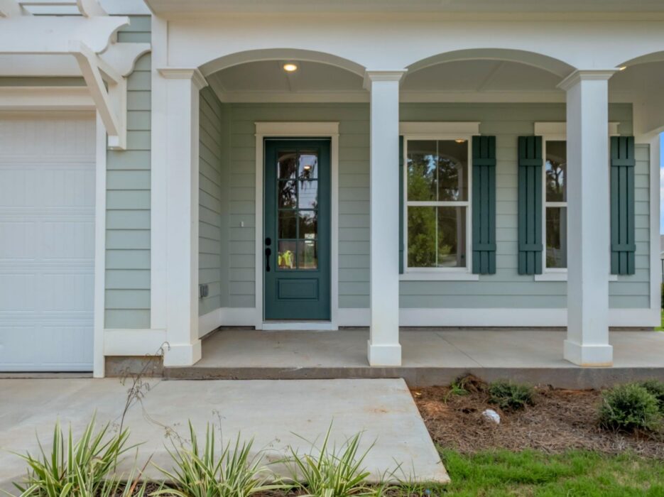 A two-story house with lit windows and a porch, gray siding, white trim, and a two-car garage, sits on a neatly landscaped yard at sunset. Text reads Virtually enhanced in the bottom right corner.